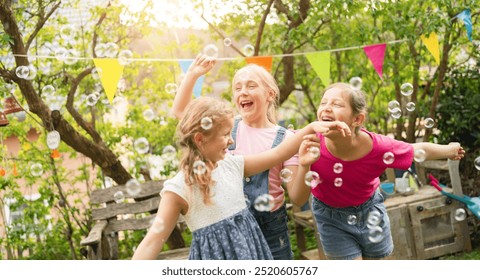 Three young girls happily play with soap bubbles at a nursery school party in a sunny garden. They laugh and dance through the bubbles, with colorful bunting and trees in the background. - Powered by Shutterstock