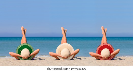 Three young girls on the beach wearing straw hats in the color of the flag of Italy. Ideal vacation concept in a resort in Italy. Focus on hats.