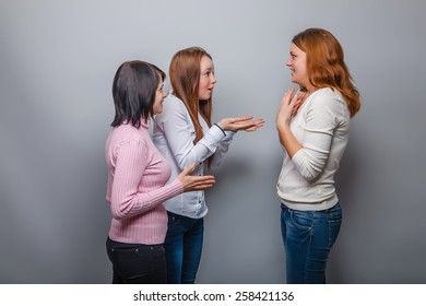 Three young girls talking and European appearance surprised on a gray background, emotions - Shutterstock ID 258421136