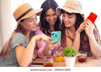 Three young happy friends in a restaurant using applications on smartphones. - Powered by Shutterstock