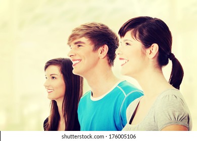 Three Young Happy Friends. Two Girls One Boy Smiling And Looking Left. Focus On Male.