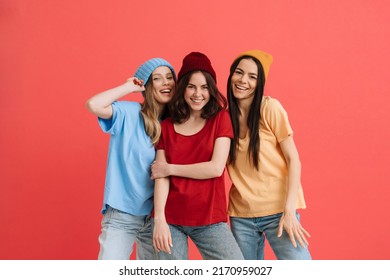 Three young happy girls smiling and posing at camera isolated over red background - Shutterstock ID 2170959027