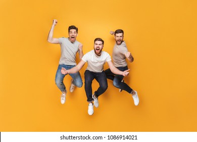 Three young happy men jumping together isolated over yellow background - Powered by Shutterstock