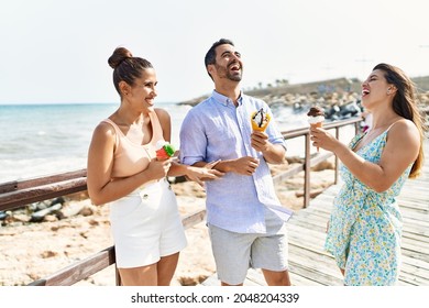 Three Young Hispanic Friends Smiling Happy Eating Ice Cream At The Beach.