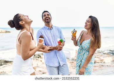 Three Young Hispanic Friends Smiling Happy Eating Ice Cream At The Beach.