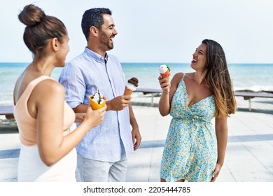 Three Young Hispanic Friends Smiling Happy Eating Ice Cream At The Beach.