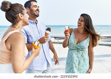 Three Young Hispanic Friends Smiling Happy Eating Ice Cream At The Beach.