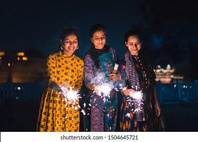 Three young Indian women with bengal fireworks, celebrating Indian Festival Diwali.