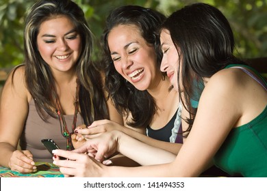 Three young ladies looking and laughing with smart phone.