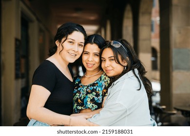 Three Young Latin American Women Embracing On The Street