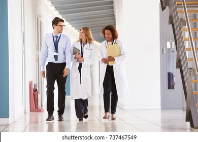 Three Young Male And Female Doctors Walking In Hospital