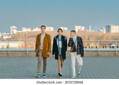 Three Young Men In Casual Clothes Walking On The Street