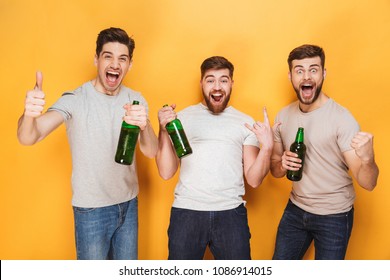 Three Young Men Drinking Beer And Celebrating Isolated Over Yellow Background