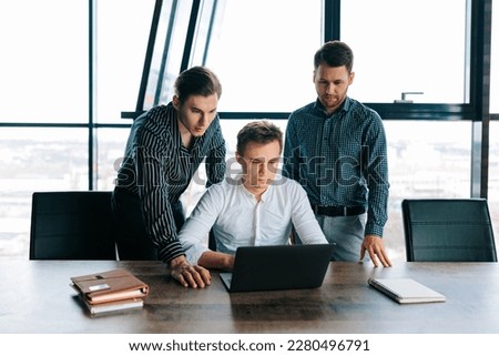 Three young men hard at work in their office, typing away on their laptops. Colleagues collaborating on a new business idea, all with their laptops at the ready.