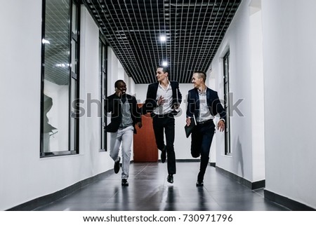 Three young men run down the corridor