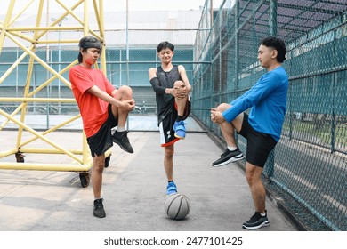 Three Young Men Stretching Their Legs Doing Warming Up On a Sport Court - Powered by Shutterstock