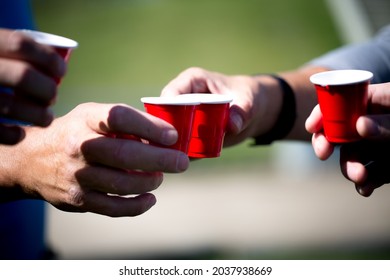 Three Young People Celebrate And Cheers Outside By Drinking Out Of Tiny Small Plastic Red Solo Shoot Cups After A Success