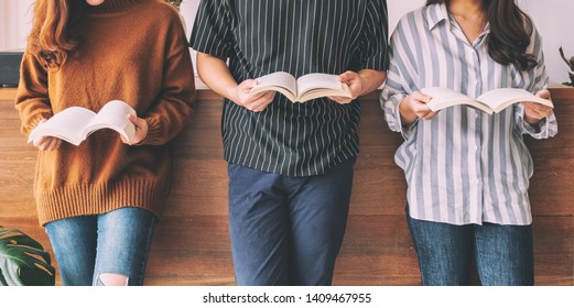 Three Young People Standing And Enjoyed Reading Books Together