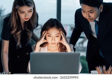 Three young professionals facing work stress while analyzing issue on laptop. Depicts digital workplace, corporate intensity, and business decision-making moments.