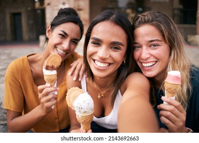 Three young smiling hipster women taking selfie outdoors in summer clothes eating ice cream. Female 20s friends having fun and enjoying summer vibes together. Holiday vacation time - Shutterstock ID 2143692663