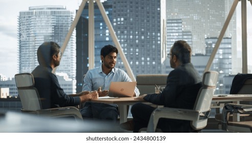 Three Young South Asian Colleagues Working in a Business Software Development Company. Indian Team Leader Using Laptop Computer, Updating Corporate Partners on Financial Market News and Trends - Powered by Shutterstock