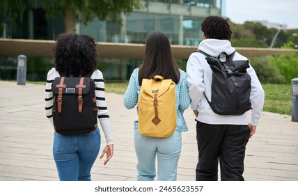 Three young students walking down a sidewalk to the University, each carrying a backpack