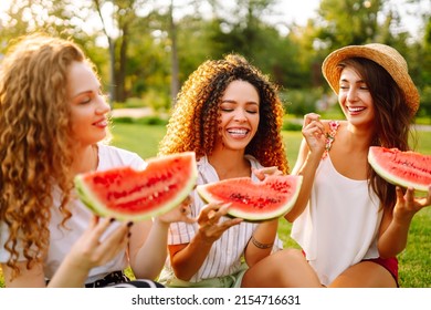 Three Young Woman  Camping On The Grass, Eating Watermelon, Laughing. People, Lifestyle, Travel, Nature And Vacations Concept. Summer Concept.