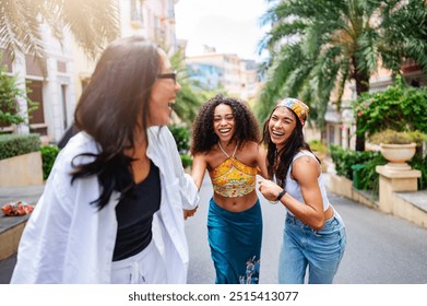 Three young women of diverse backgrounds joyfully holding hands and running down a sunny, palm-lined street in a vibrant, urban neighborhood. Their laughter and energy capture the spirit of friendship - Powered by Shutterstock