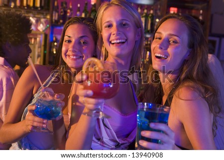 Three young women with drinks in a nightclub