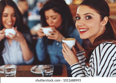 Three Young Women Enjoy Coffee At A Coffee Shop