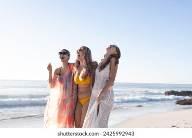 Three young women enjoy a sunny beach day. They are laughing and soaking up the seaside atmosphere in casual beachwear. - Powered by Shutterstock