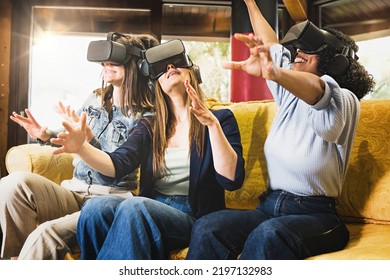 Three Young Women Sitting On The Couch Having Fun Playing A Metaverse Game Wearing 3d Googles For Virtual Reality - People And Technology Lifestyle Concept