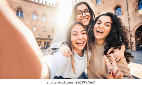 Three young women taking selfie picture with smart mobile phone on city street - Happy beautiful female friends smiling at camera outdoors -  Life style concept with cheerful girls enjoying vacation  - Powered by Shutterstock