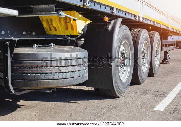 Three-axle cargo trailer with new wheels and a\
spare wheel, background. Shipping and logistics, security, trucking\
industry