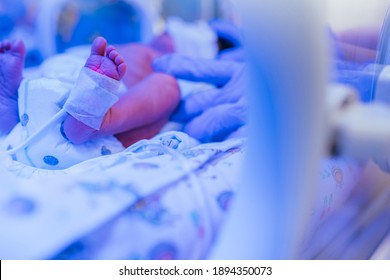 Three-day-old newborn baby in intensive care unit in a medical incubator. Feet of new born baby under ultraviolet lamp in the incubator. Newborn rescue concept. The work of resuscitation doctors.