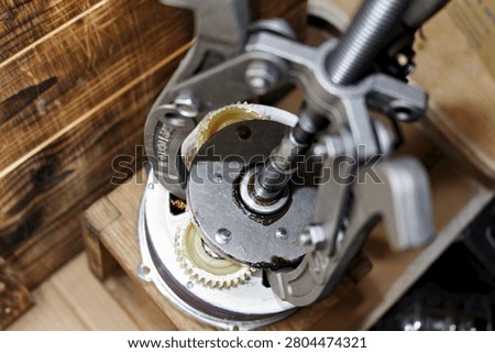 Three-jaw gear puller removing an overrunning clutch from an electric bicycle motor hub for maintenance and repair work on a wooden workshop workbench