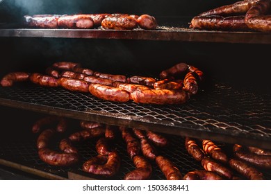 In a three-level fryer, a juicy fatty home-made pork sausage hisses and grilled on coals - fatty food
