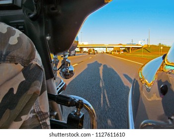 Three-wheel Motorcycle Riding On The Texas Highway At Sunset. Evening Landscape With Long Shadow Of Motorbike On Asphalt, Road Signs And Bridge.  