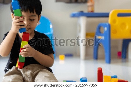 Three-years-old Asian boy builds figures from large plastic parts with interest and excitement. Children and designer concept.