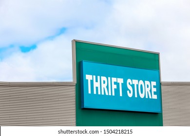 Thrift Store Sign On The Side Of A Building Against A Cloudy Sky