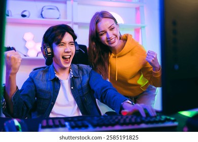 Thrilled gamer celebrates victory with a cheering friend in a neon-lit gaming setup. Perfect for esports, live streaming, competitive gaming, teamwork, digital entertainment, tech innovation content