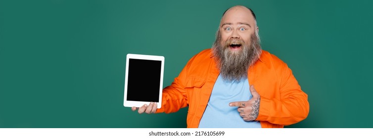 Thrilled Overweight Man Pointing At Digital Tablet With Blank Screen Isolated On Green, Banner