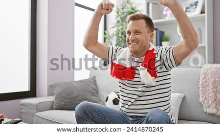 Thrilled young caucasian man sitting at home on sofa, ardently cheering and celebrating his soccer team's victory in nail-biting match on tv