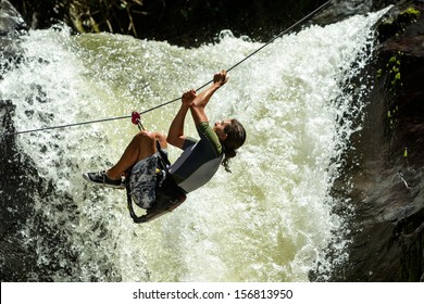 A thrilling adventure as a daredevil crosses the raging river canyon on a zipline, rappelling down the cliff next to an extreme waterfall. - Powered by Shutterstock