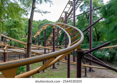 A thrilling view of a roller coaster track winding through the vibrant atmosphere of an amusement park. The photo captures the dramatic curves and loops of the steel structure against a bright