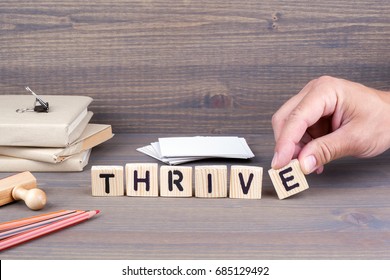 thrive. Wooden letters on dark background