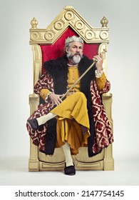 Throne of the kings. Studio shot of a richly garbed king sitting on a throne holding his scepter.