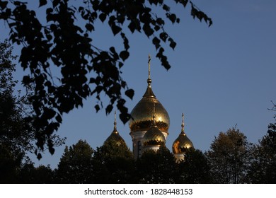 Through the blurred foliage of the tree view of the Golden domes and blue sky.Orthodox Church with a cross glistens in the sun.Russia