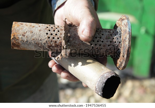 Through corrosion of the car exhaust pipe\
close up, damaged perforated tube part in mechanic man hand,\
corrosive metal\
destruction