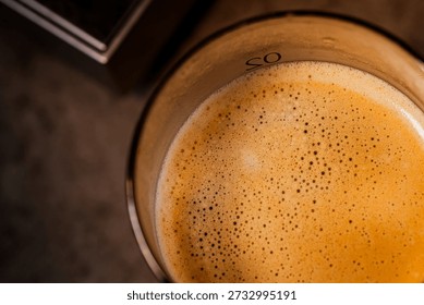 Through extremely close-up macro photography, the delicate bubbles of coffee crema and the glistening water droplets on the surface of a cold drink glass are captured, creating a warm and sophisticated afternoon atmosphere.